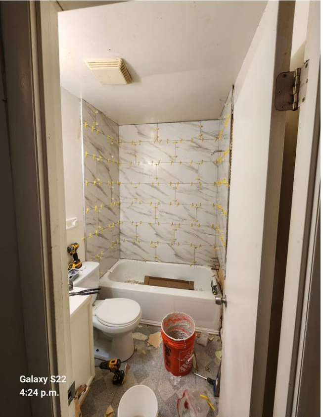 Tub surround tiled with marble-look tile and leveling clips